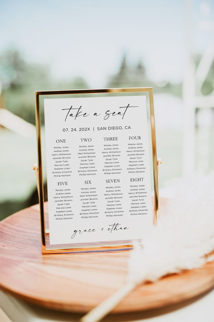 a wooden table topped with a white and gold seating plan on top of a wooden plate