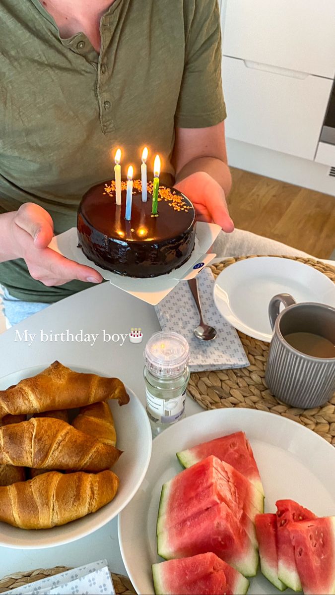 a woman sitting at a table with a cake and watermelon slices