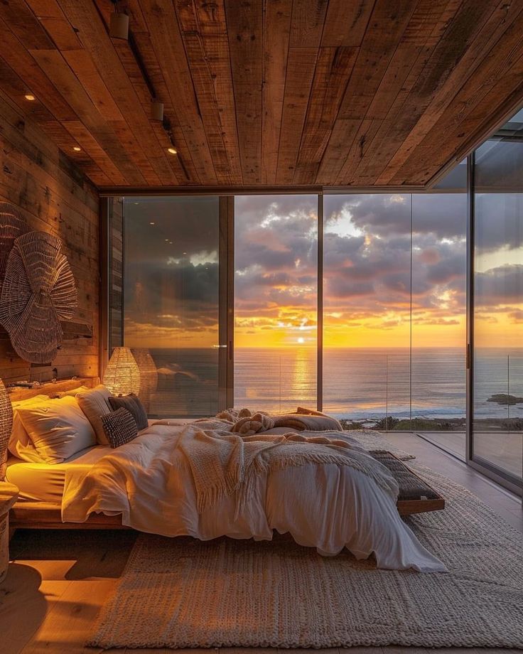 a bedroom with an ocean view at sunset