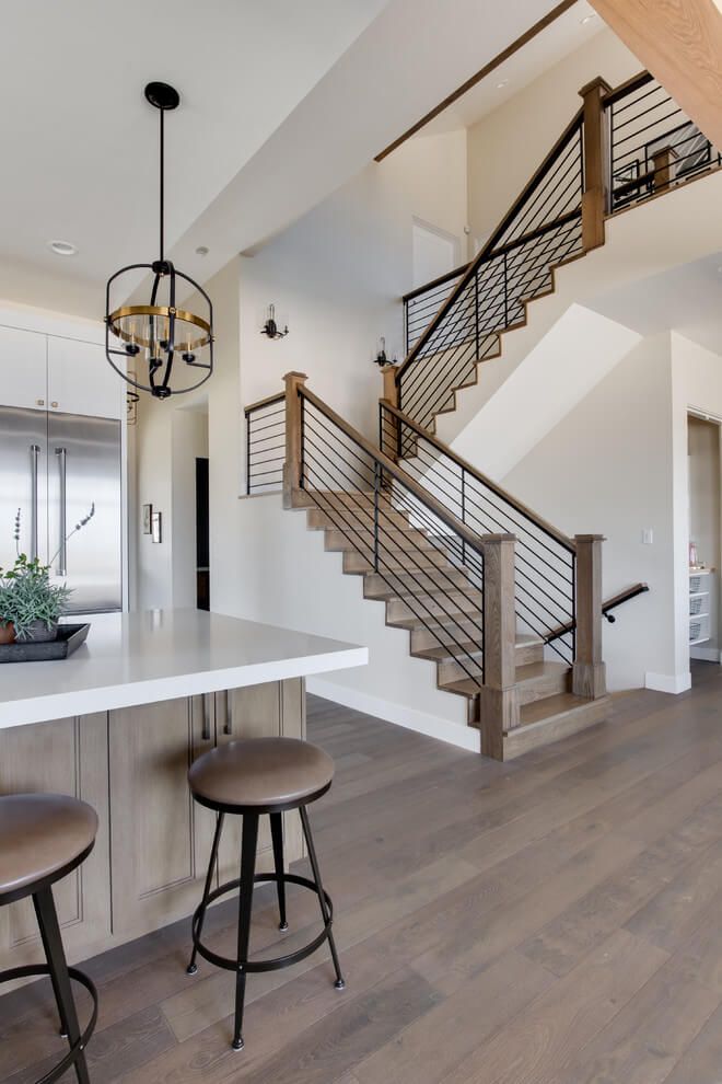 a kitchen with two stools next to a counter top and stairs in the background