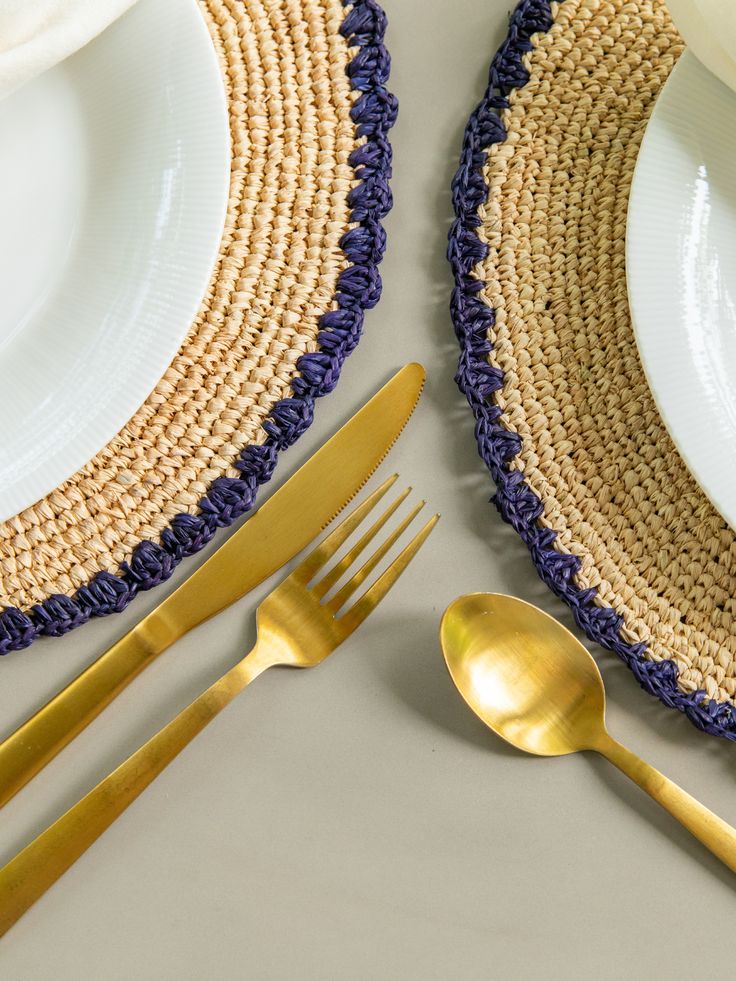 two place settings with gold forks and spoons next to each other on a table