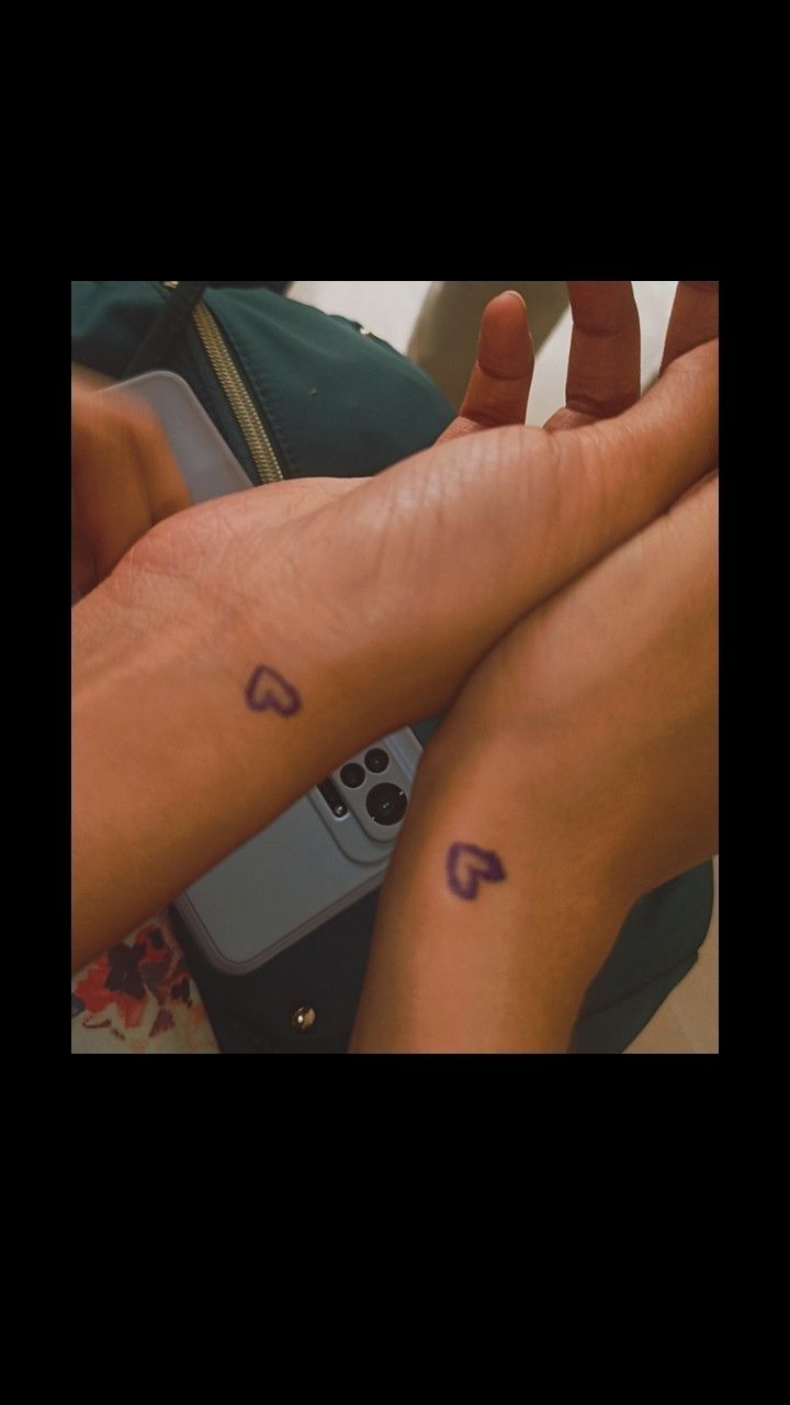 two people with matching tattoos sitting next to each other holding remote controls in their hands