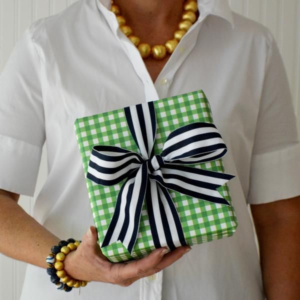 a woman is holding a green and white present