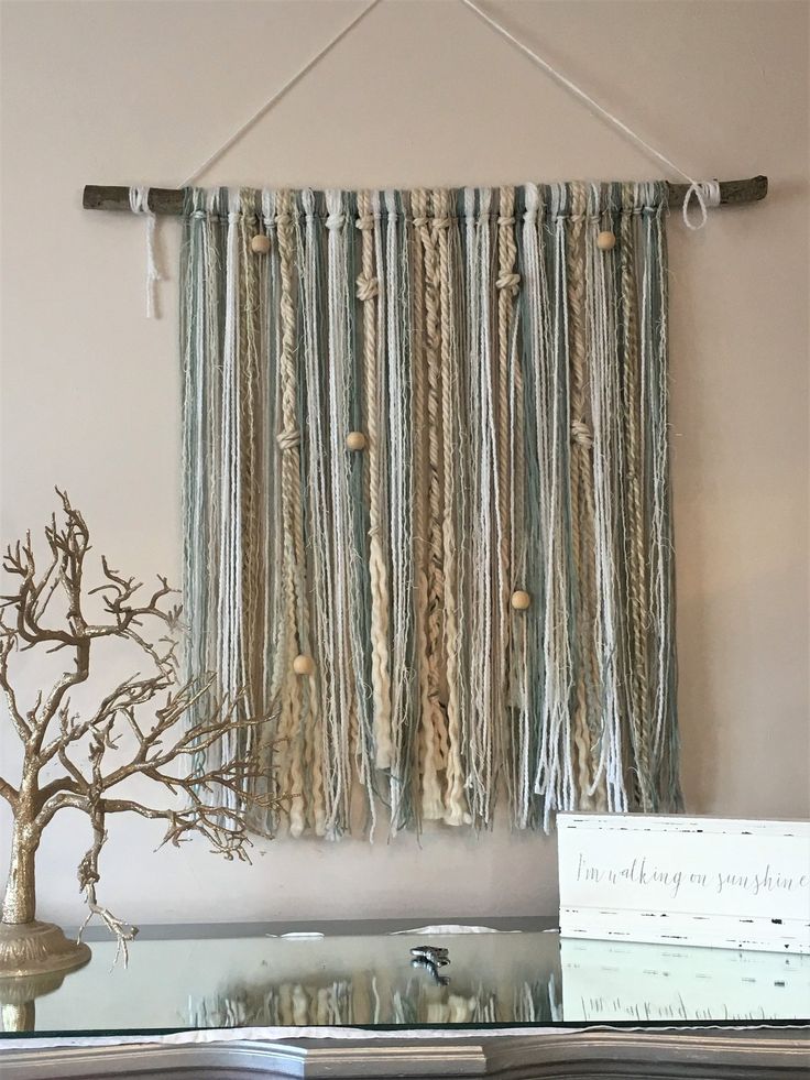 a wall hanging made out of yarn and rope with a bonsai tree in the background