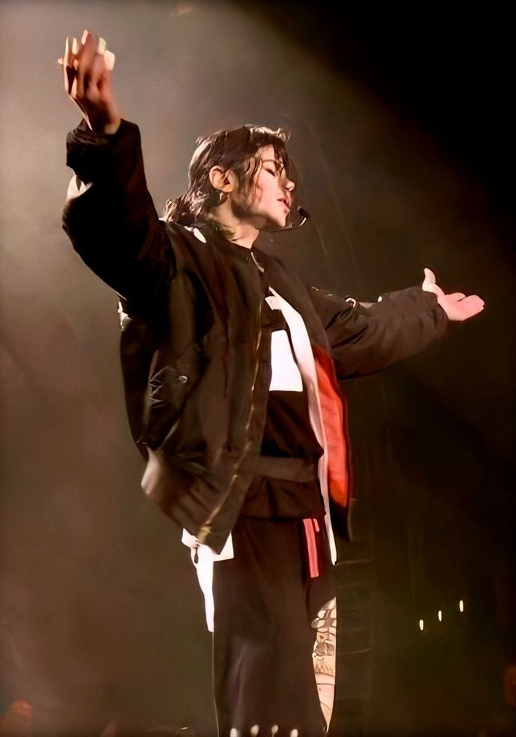 a man standing on top of a stage with his arms in the air and one hand out