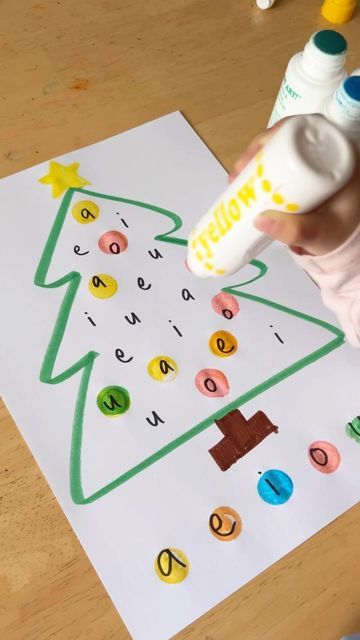 a child's hand is holding a bottle and glue to decorate a christmas tree