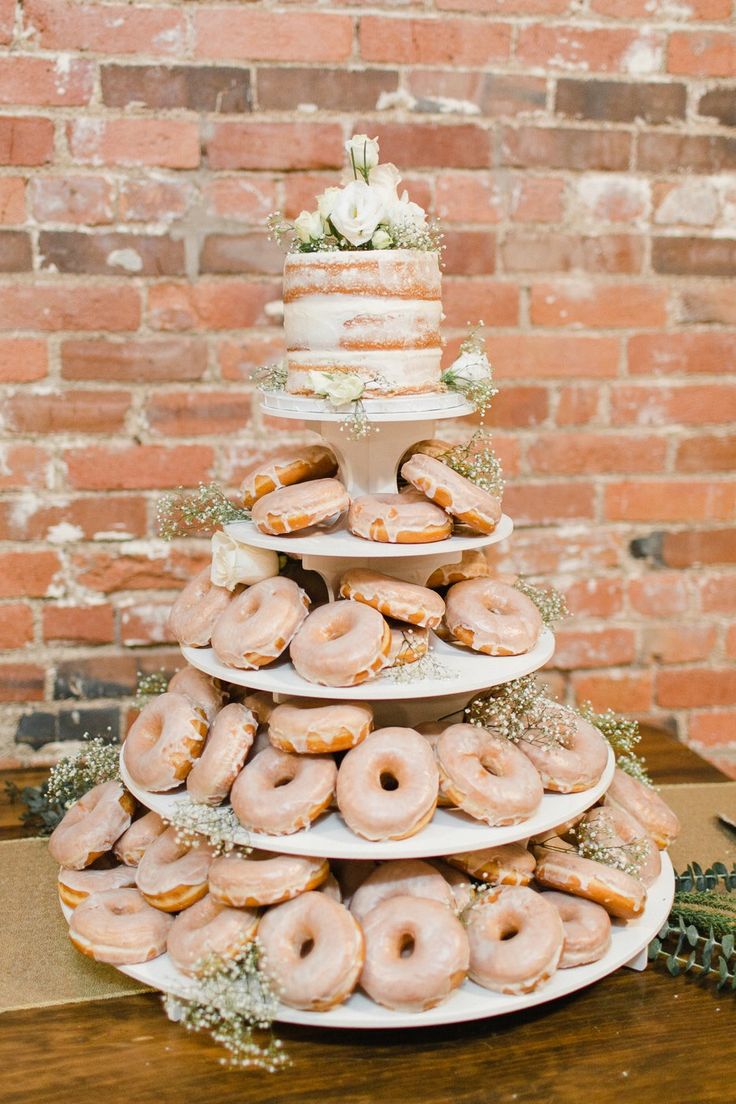 a wedding cake made out of donuts on top of a table in front of a brick wall