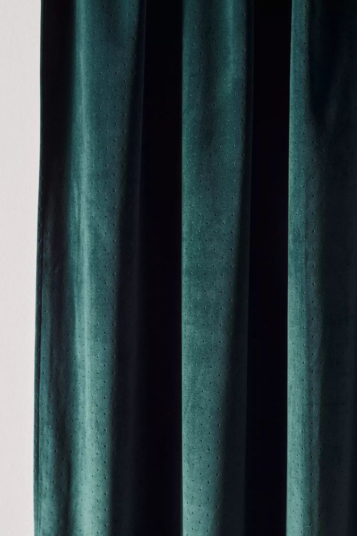 a green curtain hanging on the side of a window