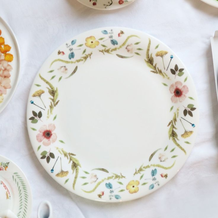 an assortment of plates and utensils are laid out on a white table cloth