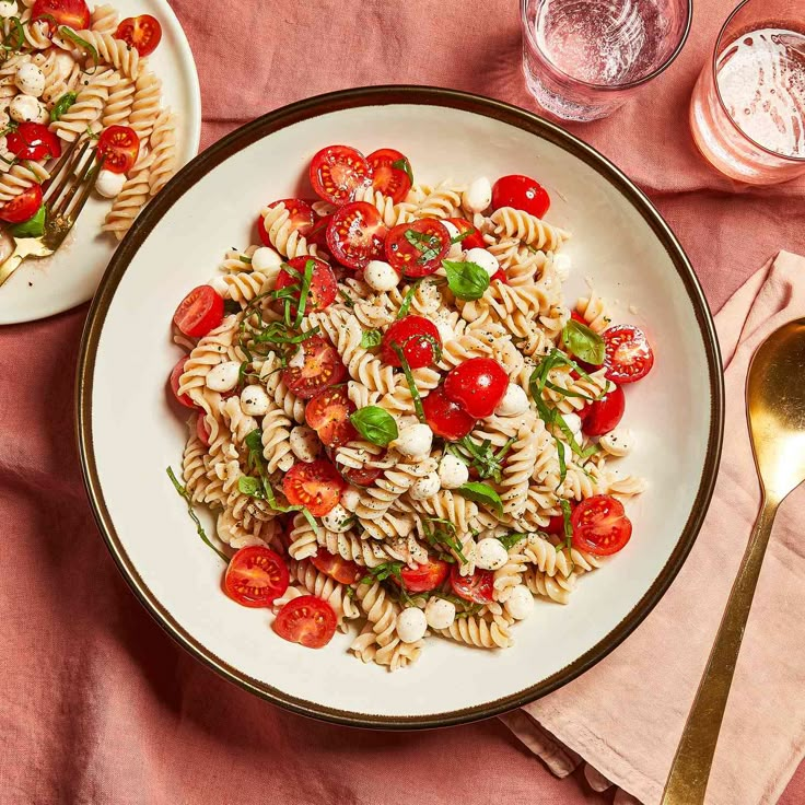 two plates of pasta with tomatoes, mozzarella and parsley on the side