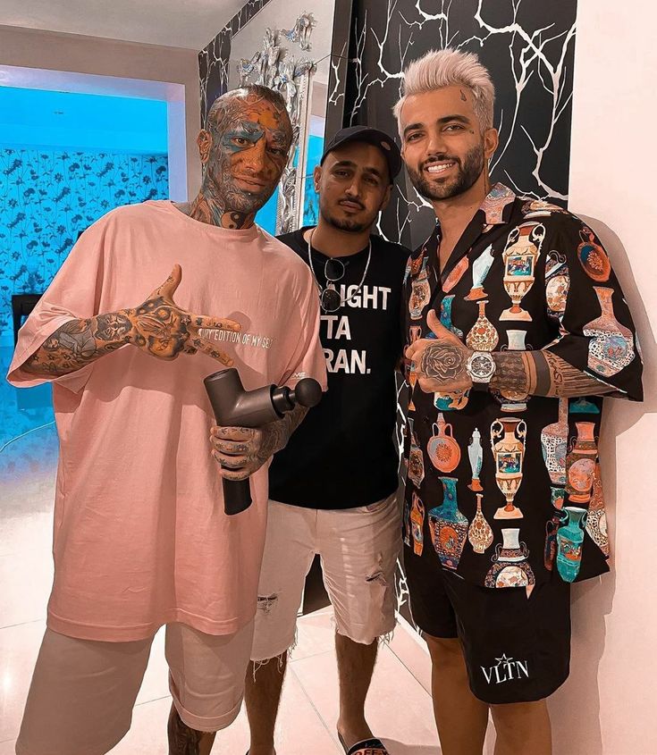 two men standing next to each other with tattoos on their arms