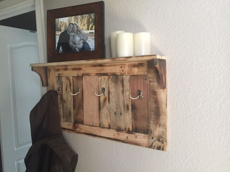 a wooden shelf with two candles on it and a picture frame hanging above the shelf