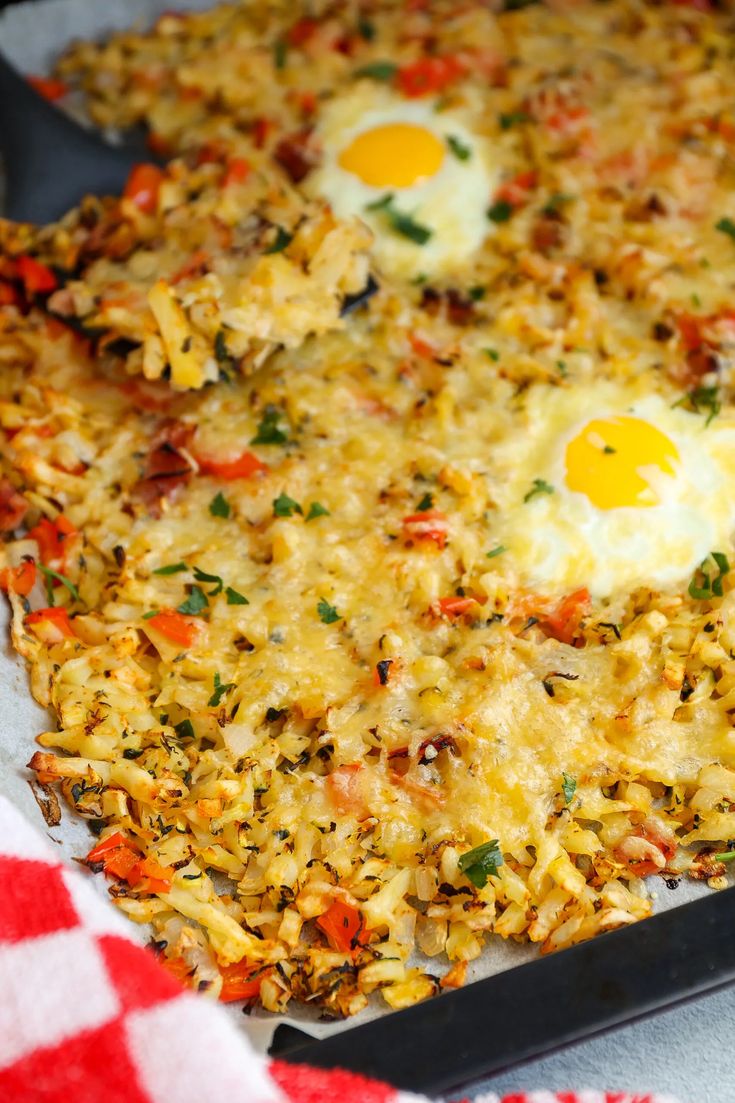 two fried eggs on top of rice in a pan with red and white checkered cloth