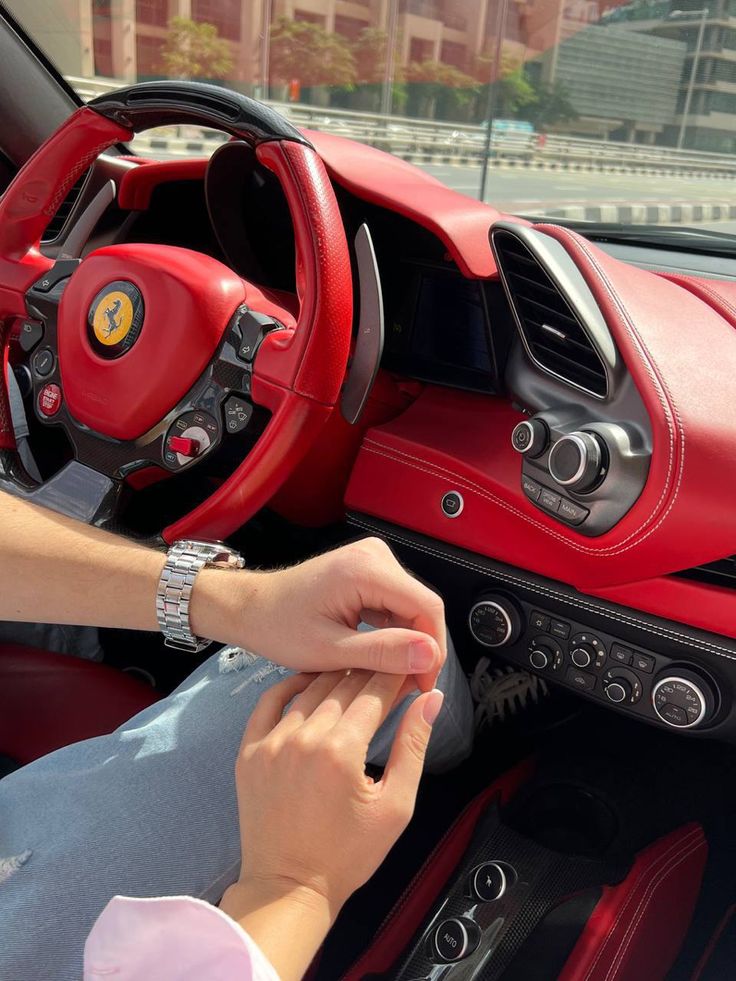 a woman driving a red sports car with her hands on the steering wheel