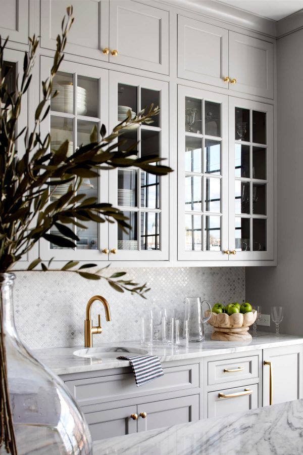 a kitchen with white cabinets and marble counter tops, gold accents on the handles and brass pulls