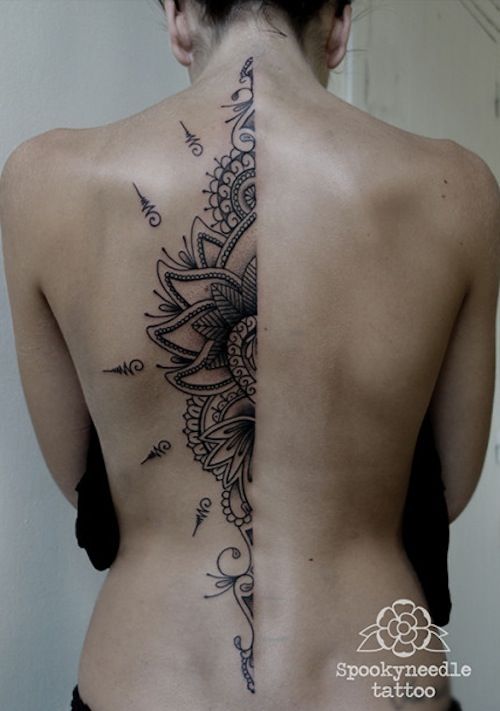 the back of a woman's body with an intricate tattoo design on her lower back