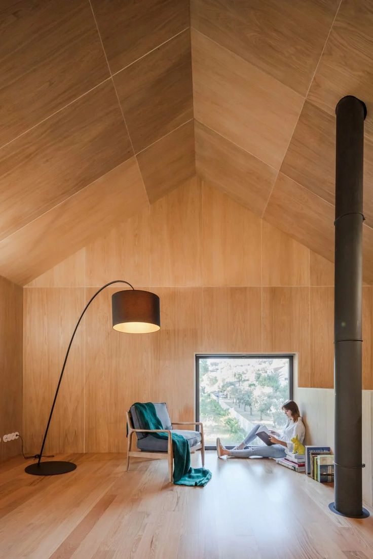 a person sitting on a chair in a room with wooden walls and flooring, while reading a book