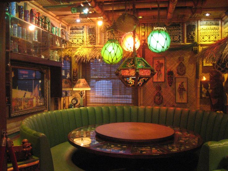 a green booth with round table and chairs in front of it, surrounded by hanging lights