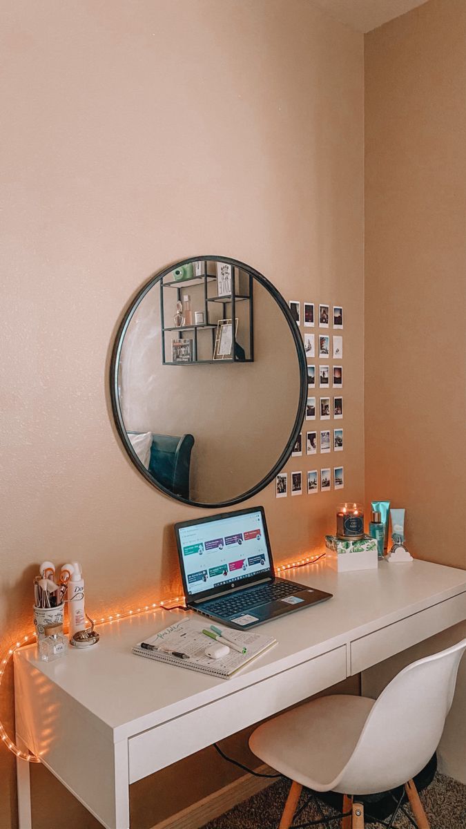 a laptop computer sitting on top of a white desk next to a mirror and chair