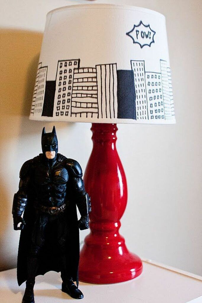 a batman lamp sitting on top of a table next to a red vase with a batman figurine