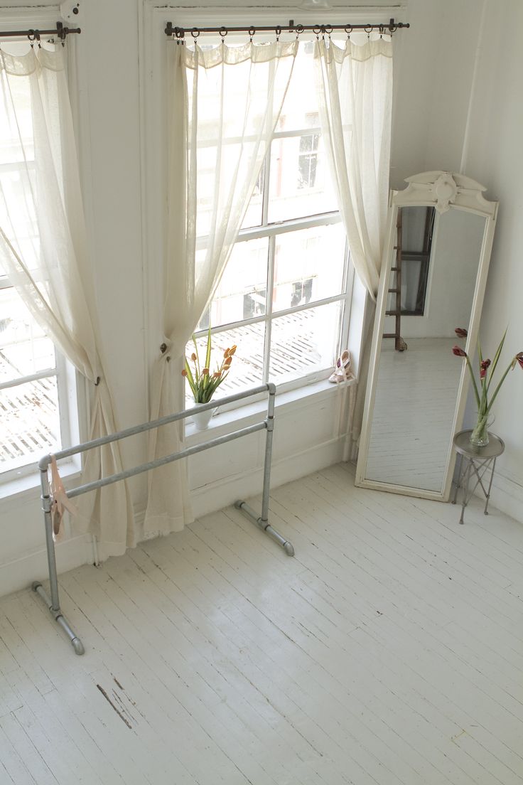 an image of a room with white walls and curtains on the window sill, in front of a mirror