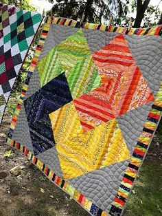 two quilts are hanging on the clothes line in front of some trees and grass