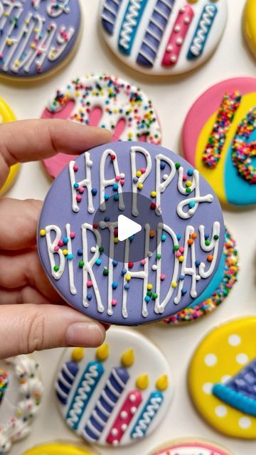 a person holding up a decorated cookie with the words happy birthday on it