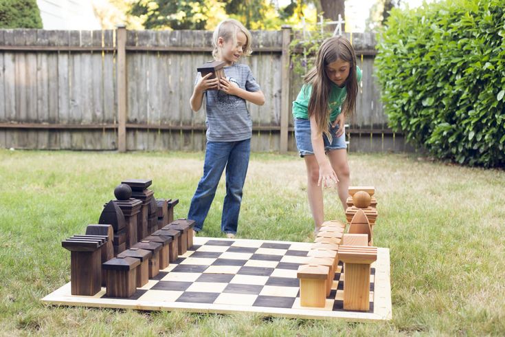 two children playing chess in the yard