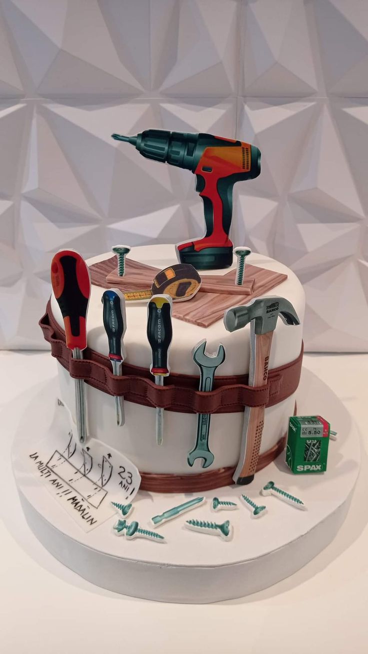 a cake with tools on it sitting on top of a white table next to a wall