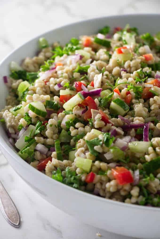 a white bowl filled with rice and veggies on top of a marble table