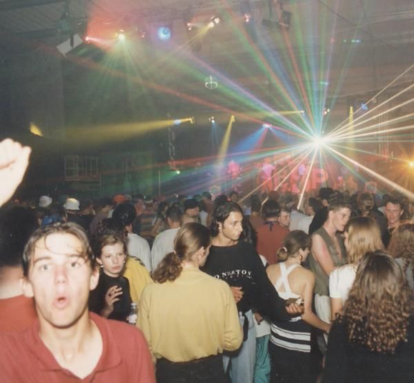 a large group of people standing around in a room with bright lights on the ceiling