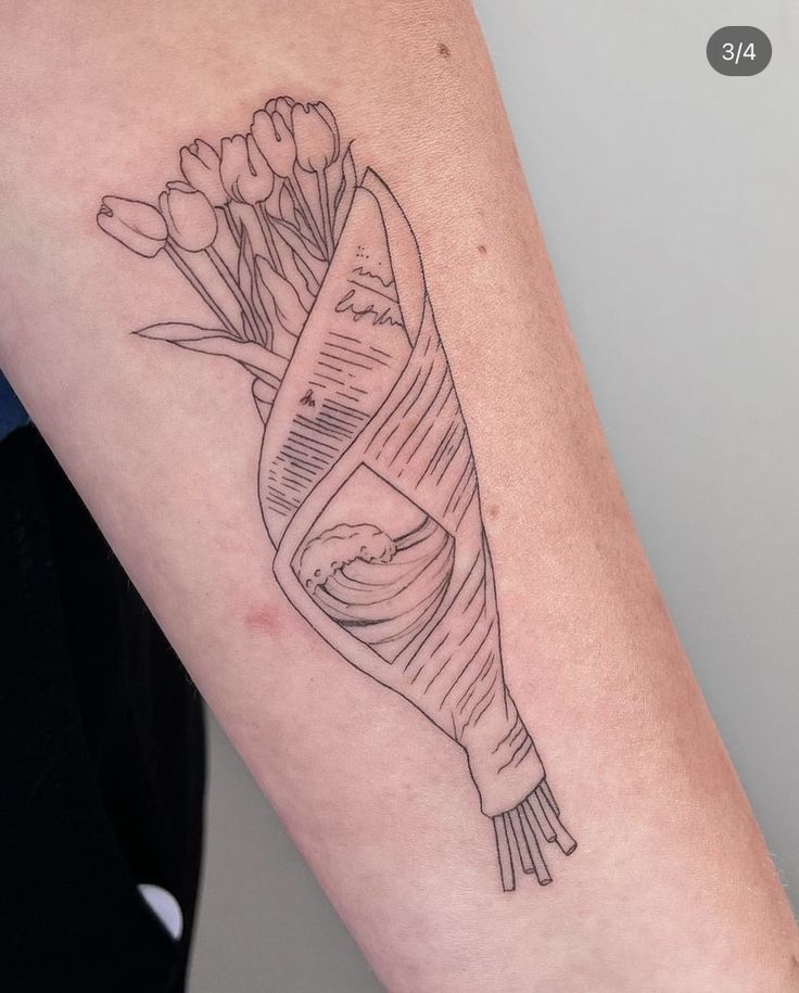 a woman's arm with a tattoo on it that has flowers wrapped in a ribbon