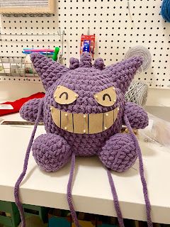 a purple stuffed animal sitting on top of a white counter next to a sewing machine