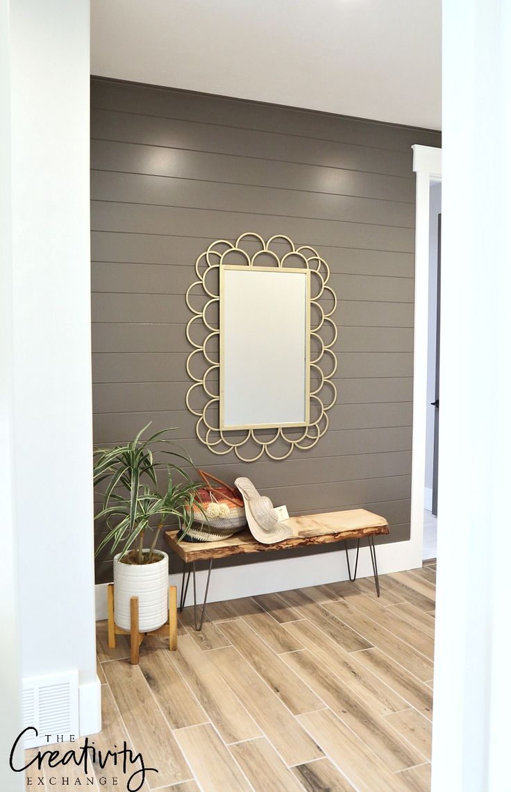 there is a bench and mirror on the wall in this room with wood flooring