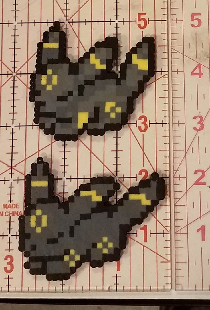 two pieces of black and yellow pixelated stickers sitting on top of a ruler