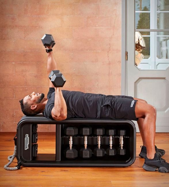 a man laying on top of a bench with two dumbs in front of him