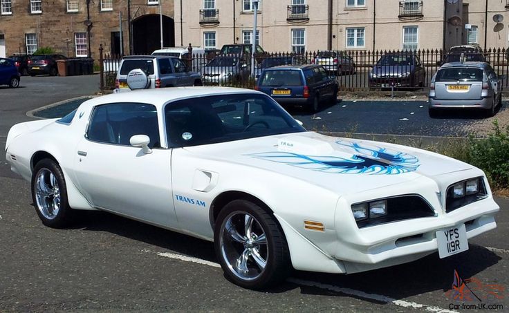 a white car with blue flames painted on it's hood parked in a parking lot