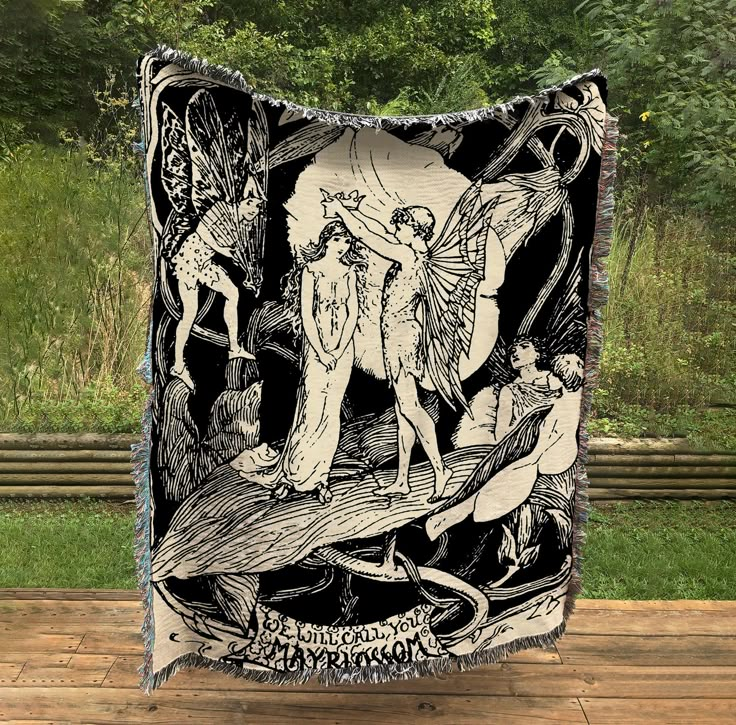 a black and white tapestry hanging on the side of a wooden floor with trees in the background