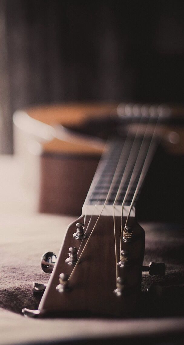 an acoustic guitar laying on the floor with its strings still attached to it's neck