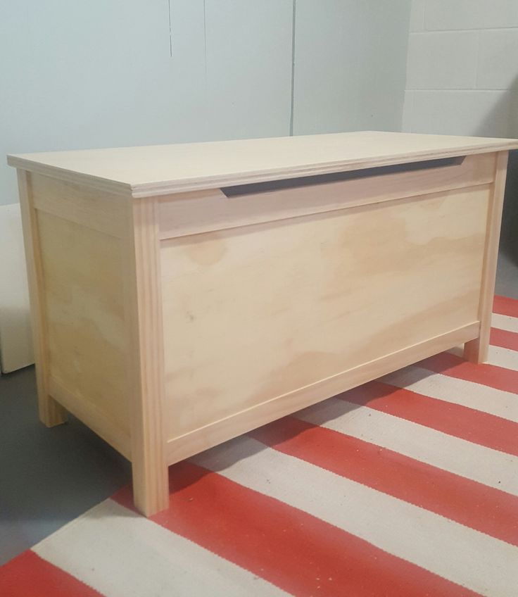 a wooden chest sitting on top of a red and white striped rug