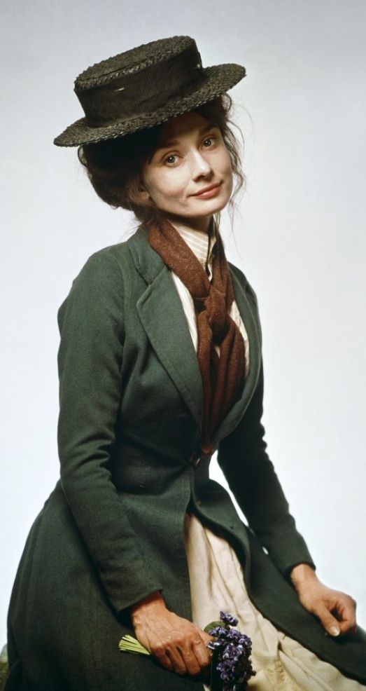 an old photo of a woman in a green coat and hat sitting on a chair