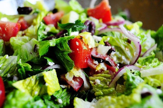 a salad with lettuce, tomatoes and other vegetables on the side is ready to be eaten