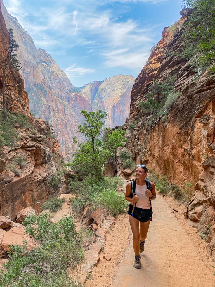 a woman is running down a trail in the mountains