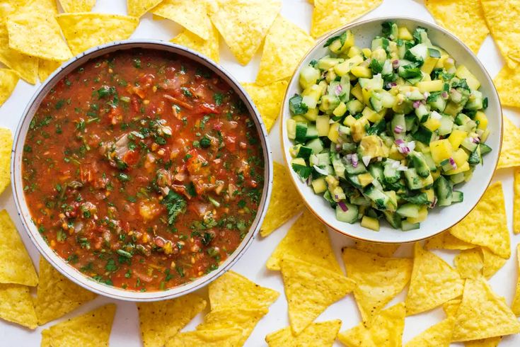 two bowls filled with salsa next to some tortilla chips