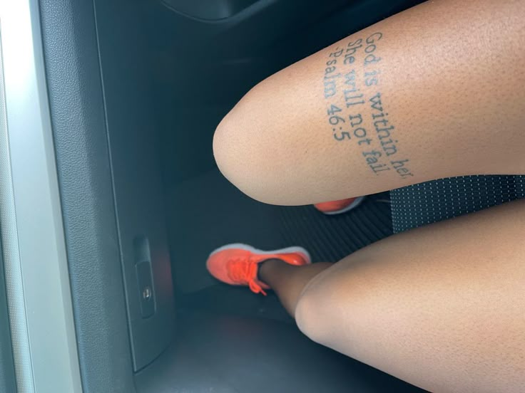 the legs and ankles of a woman with tattoos on her leg, sitting in a car