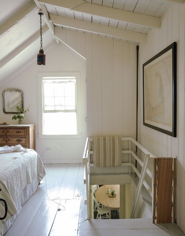 an attic bedroom with white walls and wood flooring, along with a bed in the corner