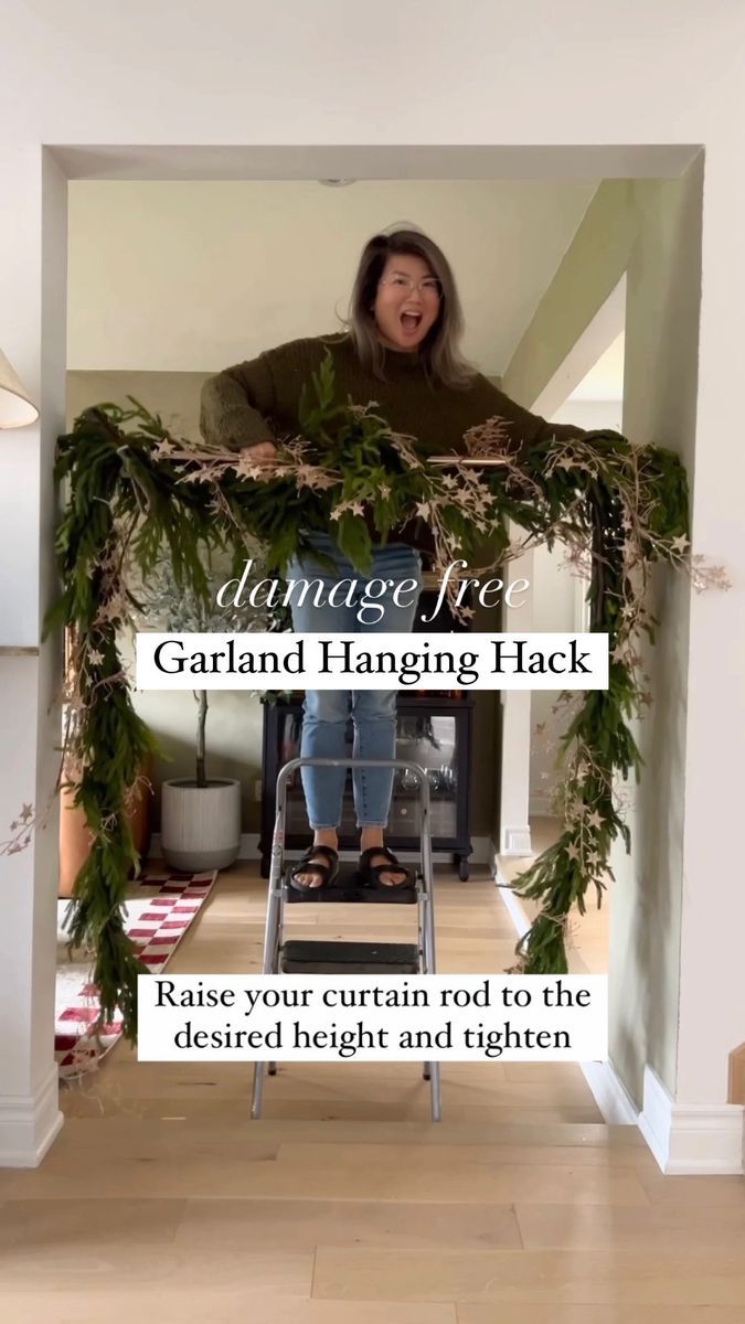 a woman sitting on top of a chair in front of a fireplace with greenery