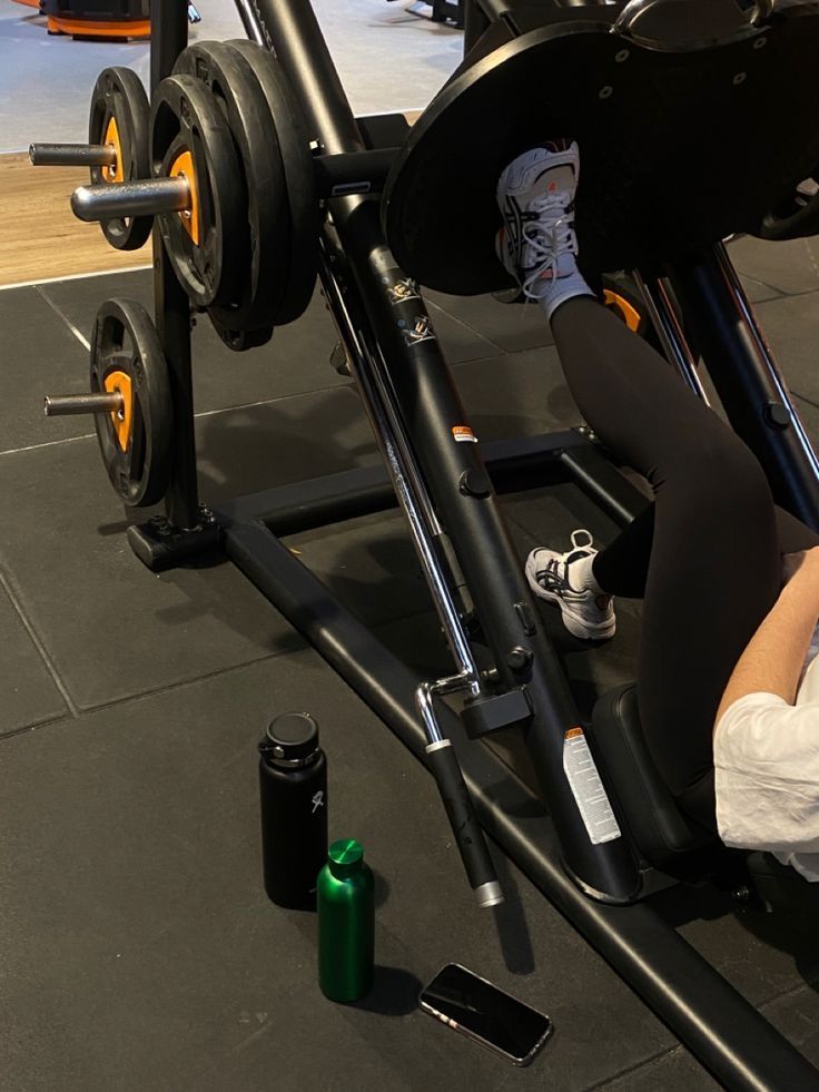 a woman sitting on top of a bench next to a barbell exercise machine in a gym