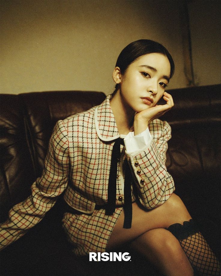 a woman sitting on top of a brown leather couch wearing a shirt and tie with her hand under her chin