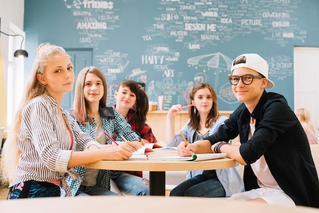 a group of young people sitting at a table in front of a chalkboard wall